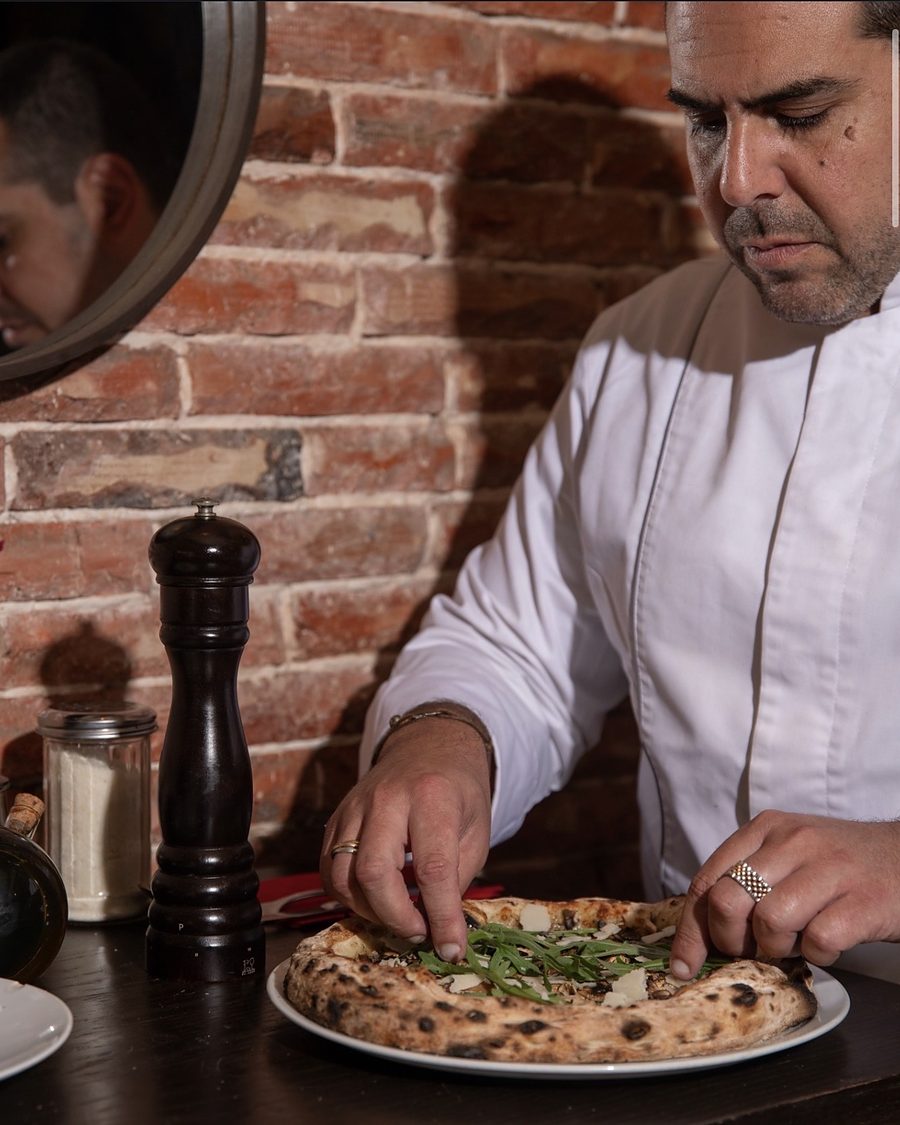 The pizzaiolo of Trattoria del Papa dressing a pizza